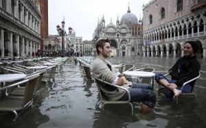 Tourists sit in St. Mark Square during a period of seasonal high water in Venice